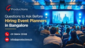 Realistic blog banner featuring an elegant event venue in Bangalore with blue stage lighting, a decorated banquet hall, floral centerpieces, and gold accents, titled “Questions to Ask Before Hiring Event Planners in Bangalore.”